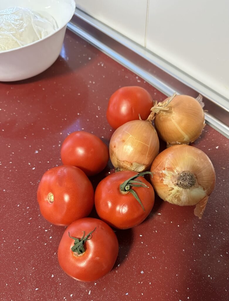tomato and onion on a red kitchen counter