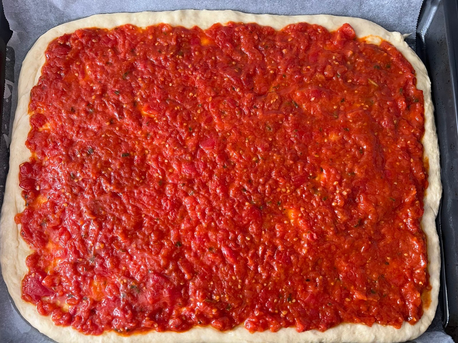 Masa de pizza con salsa de tomate casera.