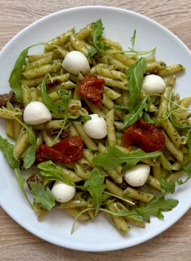 Pesto pasta dish with mozzarella, arugula and sun-dried tomatoes