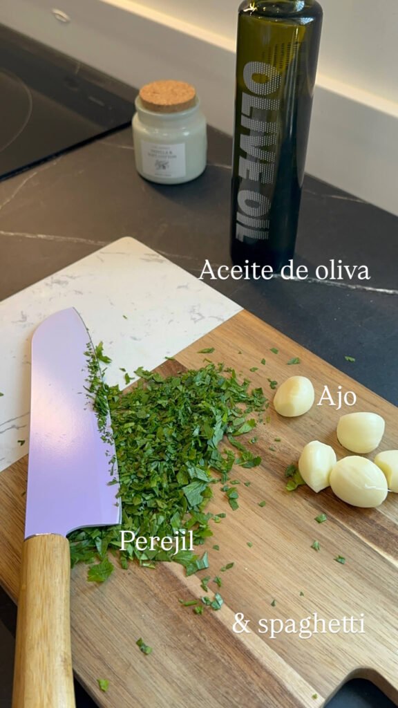 tabla de cortar con dientes de ajo perejil picado y una botella de aceite de oliva virgen extra