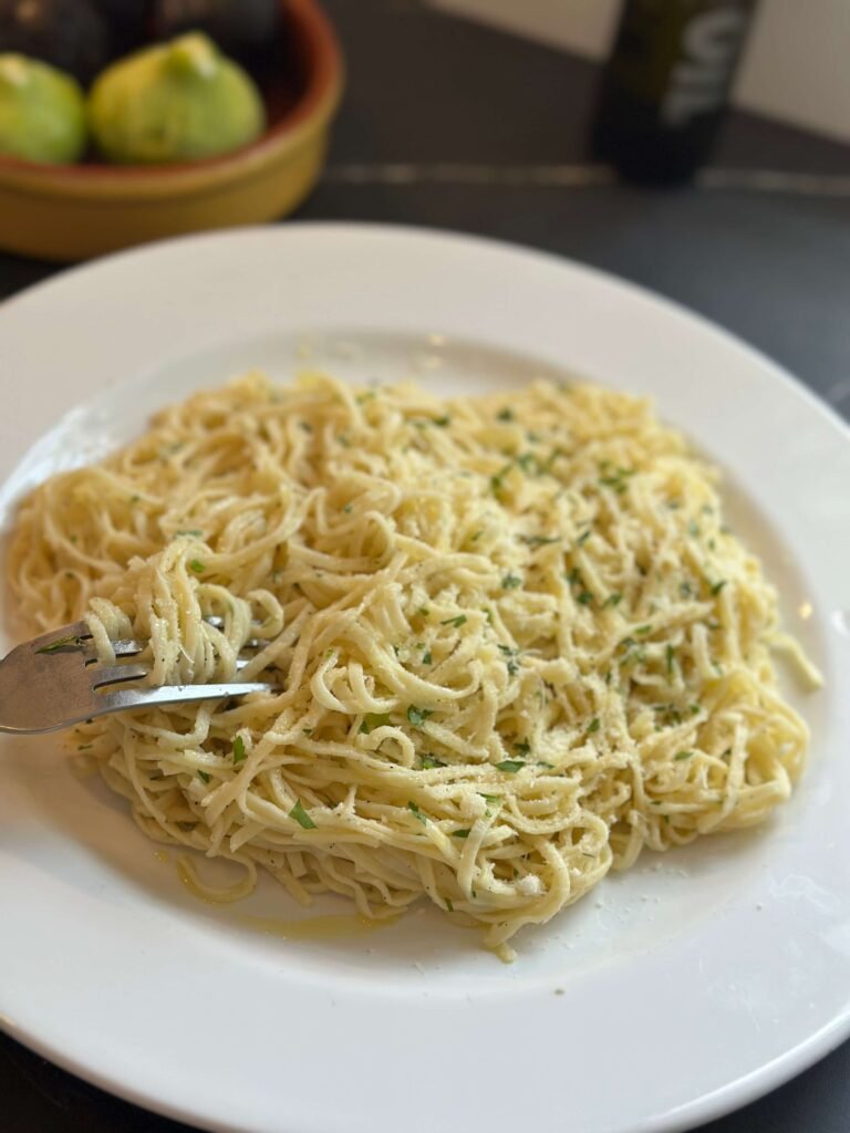 plate of spaghetti with garlic and oil with a fork ready to eat
