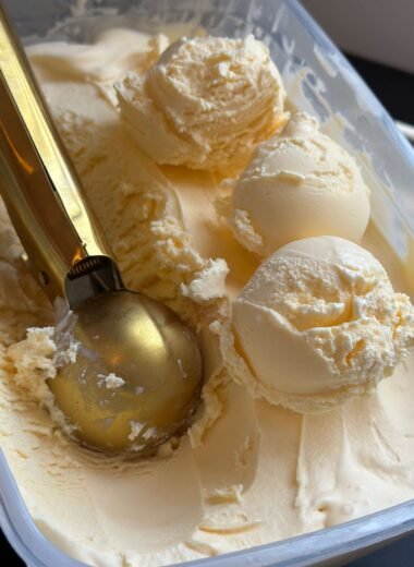 Tarrina de helado de vainilla con tres bolas de helado y una cuchara dorada