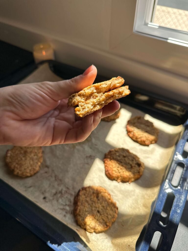 Mano cogiendo galletas de avena con una bandeja de horno con galletas detrás